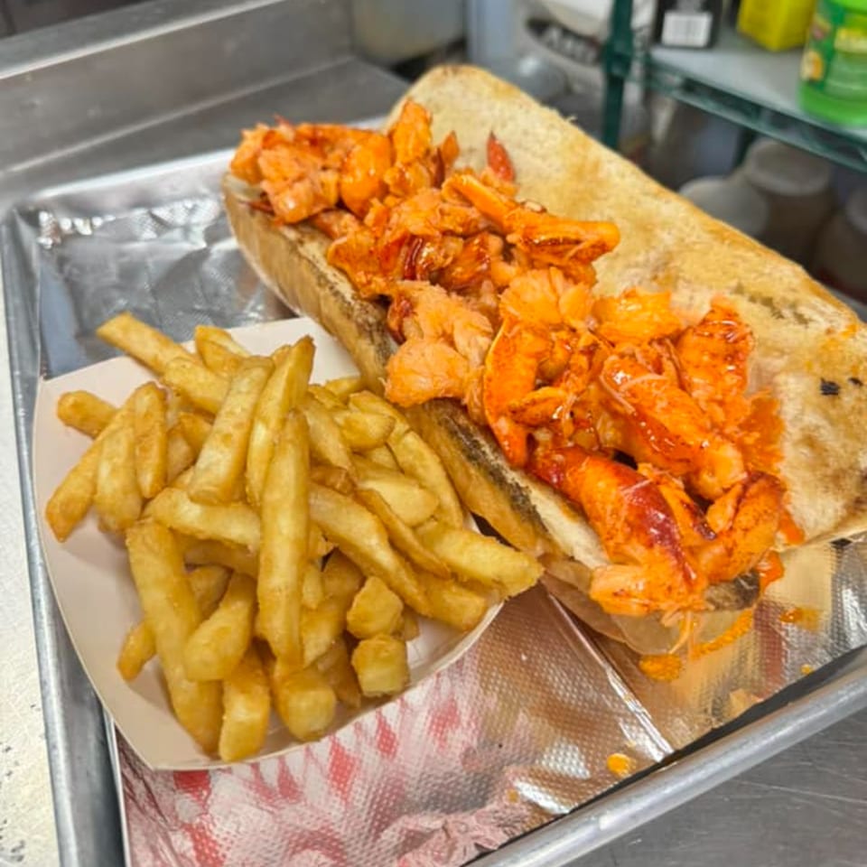 Willys Pub & Grub's lobster roll with a side of golden french fries on a metal tray.