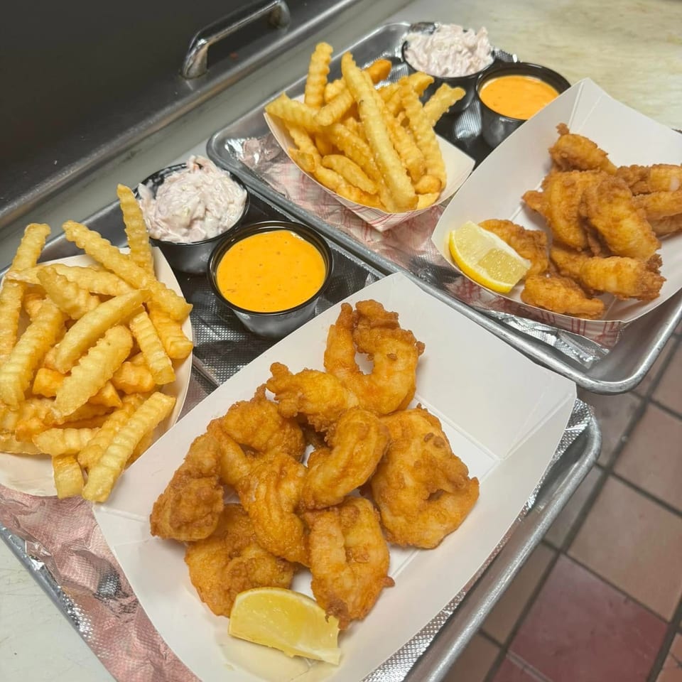 Three trays of fried shrimp and crinkle-cut fries, with coleslaw and dipping sauces.
