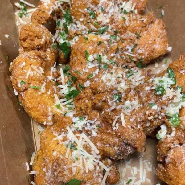Golden-brown fried seafood bites, possibly shrimp or scallops, topped with grated cheese and fresh parsley.
