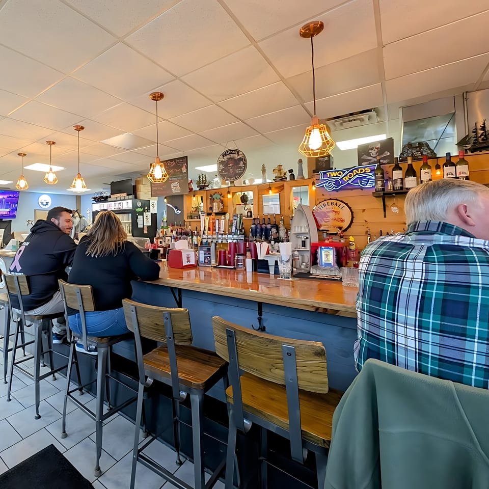 Customers seated at the long wooden bar of Willys Pub & Grub, adorned with nautical decor.